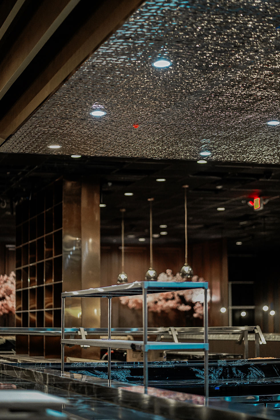 Black marble sushi bar under pendant lights at Umiya Raleigh, an all you can eat sushi and hot pot restaurant