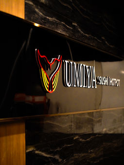 Red Umiya Sushi Hotpot sign glowing on black marble at the Raleigh restaurant