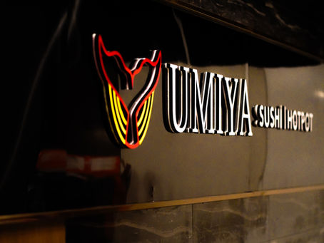 Red Umiya Sushi Hotpot sign glowing on black marble at Umiya Raleigh near North Hills