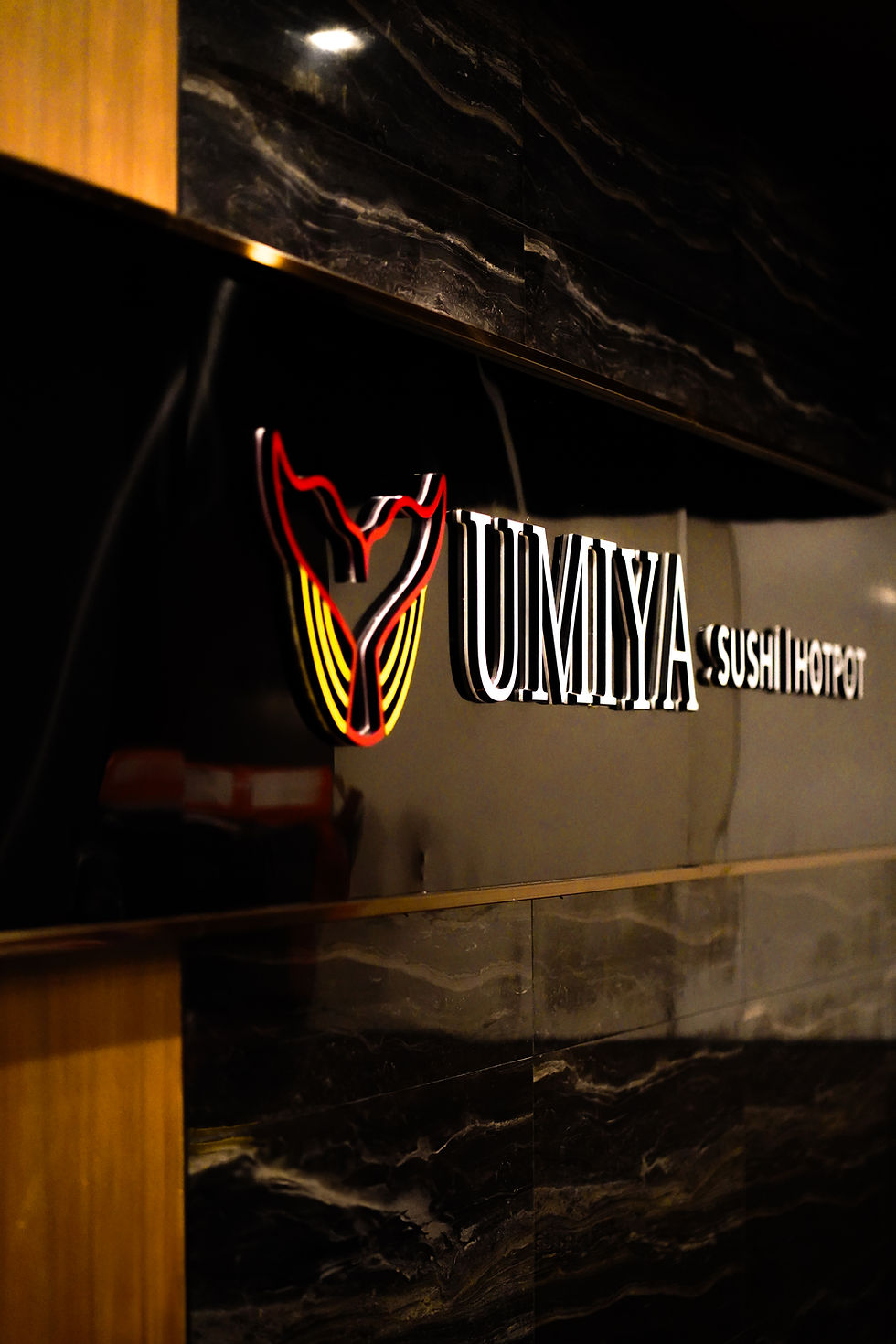 Red Umiya Sushi Hotpot sign glowing on black marble at Umiya Raleigh near North Hills